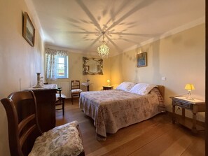 A bedroom with a bed, a desk, a chair, a table, a lamp, and a mirror. - ANIOTZ-BEHEREA - SARE (SARE)