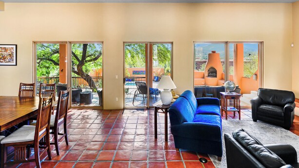 A spacious living area with a dining table, blue sofa, and black armchair. Large windows offer views of the outdoors. - Sonoran Retreat w/ Hot Tub near Starr Pass Golf & Saguaro Park (Tucson)