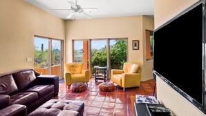A spacious living room with a leather sofa, yellow armchairs, and a flat-screen TV. - Sonoran Retreat w/ Hot Tub near Starr Pass Golf & Saguaro Park (Tucson)