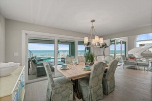 Un comedor con vistas al océano, un piano y un balcón con piscina.