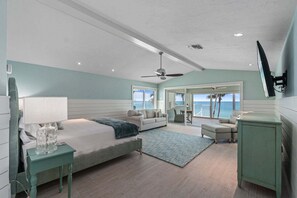 Un dormitorio con cama, escritorio, silla, televisión y vista al océano.