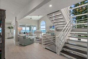 Un interior moderno con una escalera, una zona de estar y vistas al océano.