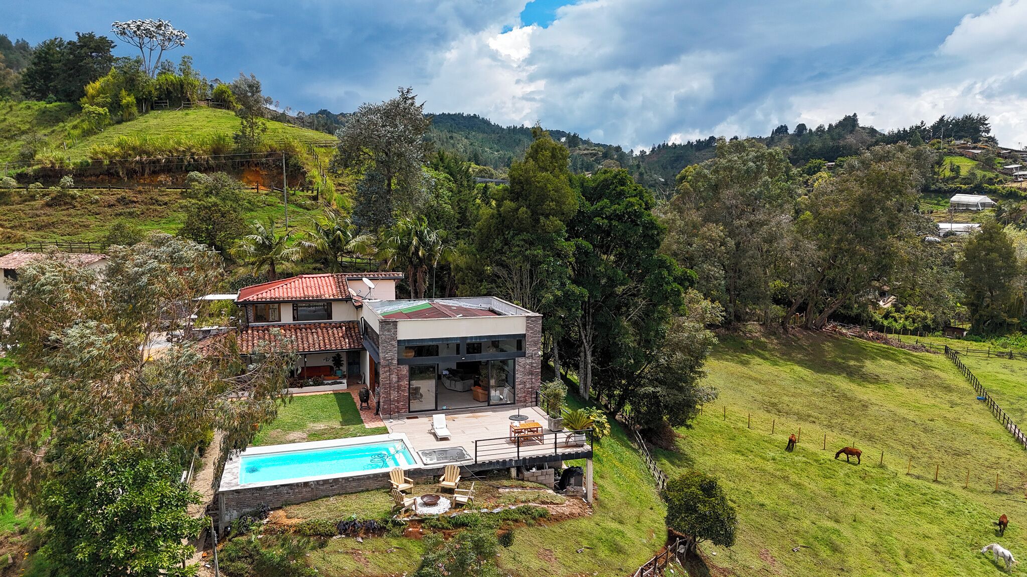 A modern house with a swimming pool, surrounded by lush greenery and hills.