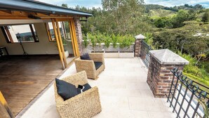 A patio with wicker furniture and a view of a hilly landscape. - Sahara Lodge: Nature, Design & Arabian Horses (El retiro)