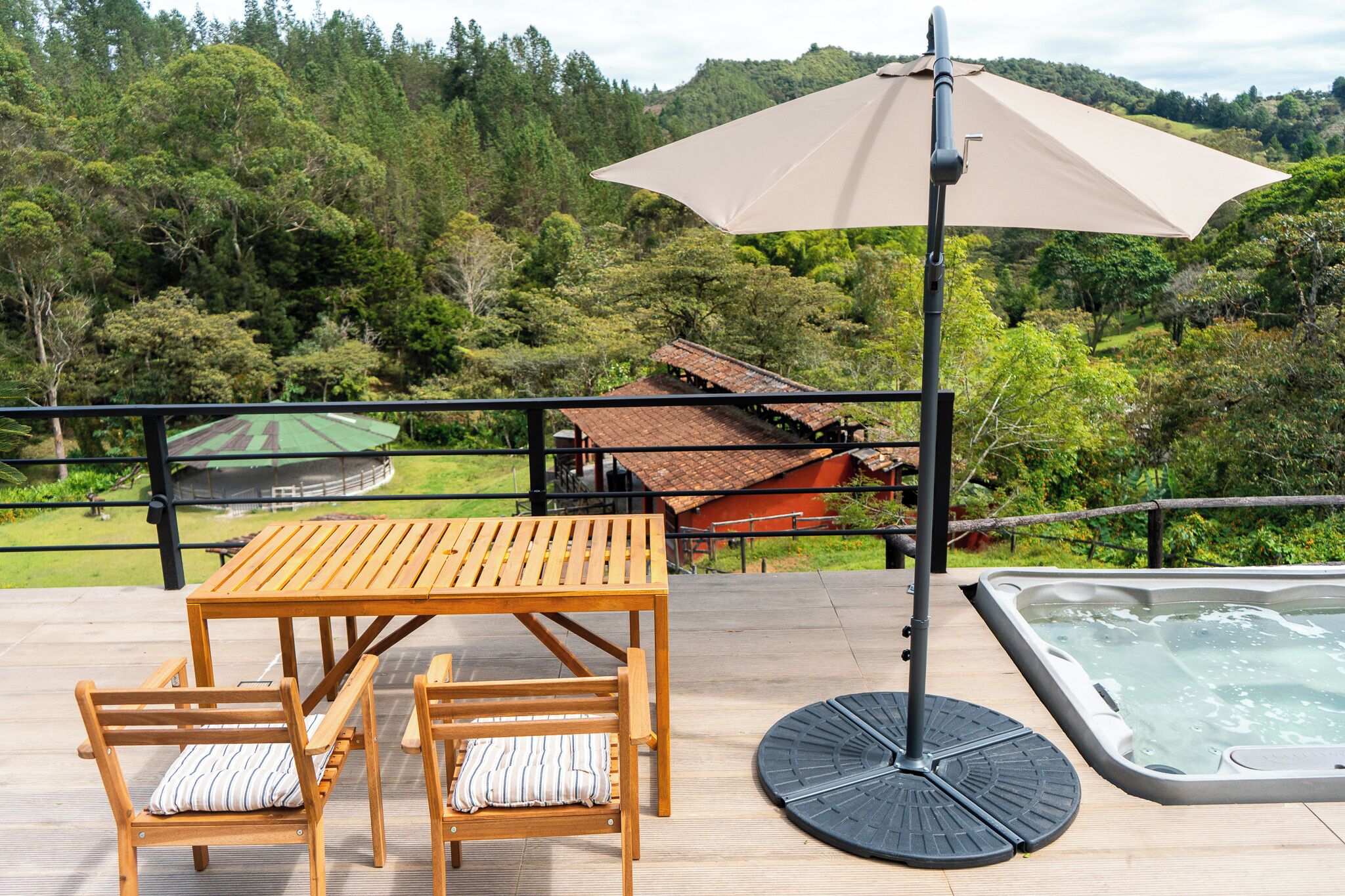 Eine Holzterrasse mit Tisch, Stühlen, einem Whirlpool und einem großen Sonnenschirm.