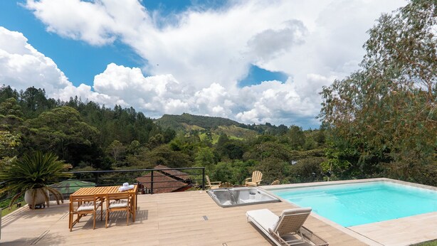 A pool area with a wooden deck, lounge chairs, and a hot tub. - Sahara Lodge: Nature, Design & Arabian Horses (El retiro)