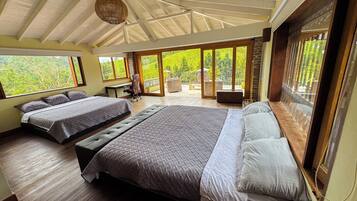 A bedroom with two beds, a desk, and a view of the outdoors.