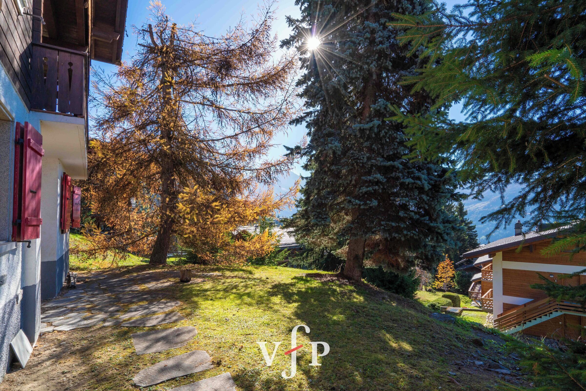 A pathway leading to a building with a wooden staircase and a view of trees and a clear sky.