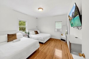 Habitación de hotel con dos camas, televisión y escritorio.