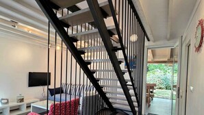 Una sala moderna con escalera, un sofá, un televisor y un comedor.