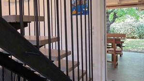 Una escalera con barandillas negras que conduce a un patio abierto con una mesa y sillas de madera.