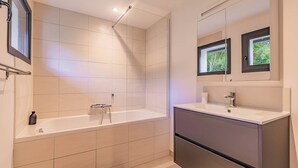Un baño moderno con una bañera, un tocador con espejo y una ventana.