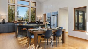 Una cocina amplia con una isla central, ventanas grandes y un comedor con sillas.