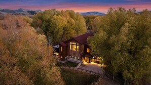 Una casa moderna con una amplia terraza, rodeada de árboles y montañas.