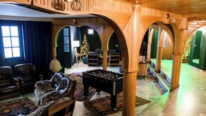 Una habitación acogedora con sofás de cuero, mesa de fútbol y un árbol de Navidad.