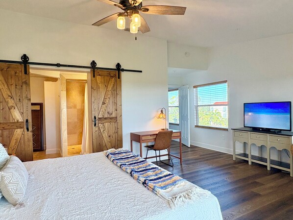 A bedroom with a bed, a desk, a chair, a TV, and a ceiling fan. - Private balconies, Walk to Holmes Beach, sleeps 8, access to heated pool (Holmes Beach)
