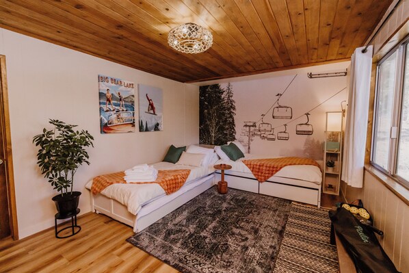Una habitación acogedora con techo de madera, cama con alfombra estampada, planta en maceta y un cartel de telesilla.