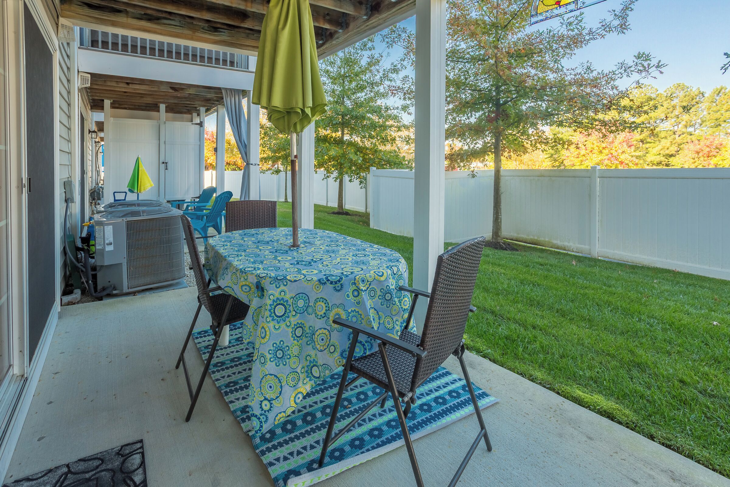 Une terrasse extérieure avec une table ronde, des chaises et un parasol vert.