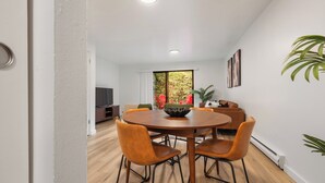 Een moderne eethoek met een ronde houten tafel, lederen stoelen en een centraal geplaatste schaal.
