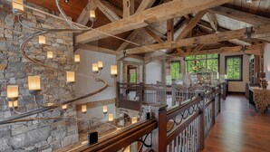 Un ambiente spazioso con travi a vista in legno, pareti in pietra e una ringhiera in legno che si affaccia su un livello inferiore.