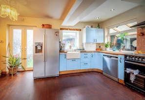 Cucina con frigorifero, lavastoviglie, forno e finestra vista su spazi verdi.