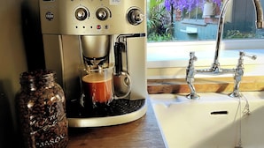 A De'Longhi MAGNIFICA espresso machine with a glass carafe and a jar of coffee beans on a countertop.