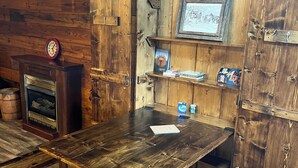 A rustic wooden dining table with benches, a vintage clock, and a fireplace.