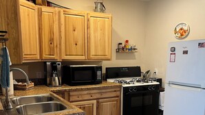 A kitchen with wooden cabinets, a microwave, a stove, a sink, and a refrigerator.