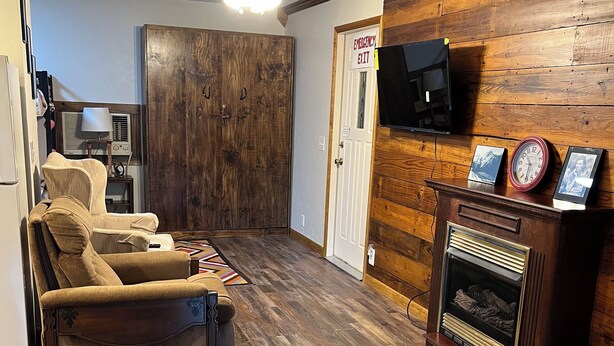 A living room with a fireplace, a ceiling fan, and a television mounted on the wall.