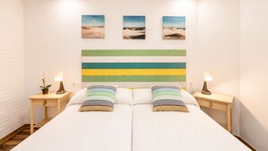 A double bed with striped pillows, a striped headboard, bedside tables with lamps, and three landscape paintings on the wall. - Brisas de Andrín - Near Andrín Beach, Llanes (Andrin)