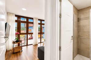 Ein modernes Badezimmer mit Dusche, Holzboden und Blick ins Freie.