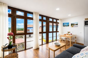 Ein geräumiger Wohnbereich mit großem Fenster, einem Esstisch und einer Couch.