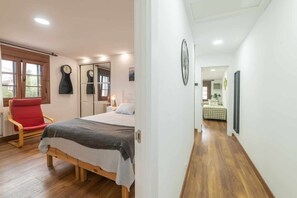 A bedroom with a bed, a red chair, and a wooden floor. - Apartment in Llanes near the beach - El Refugio de Andrín (Andrin)