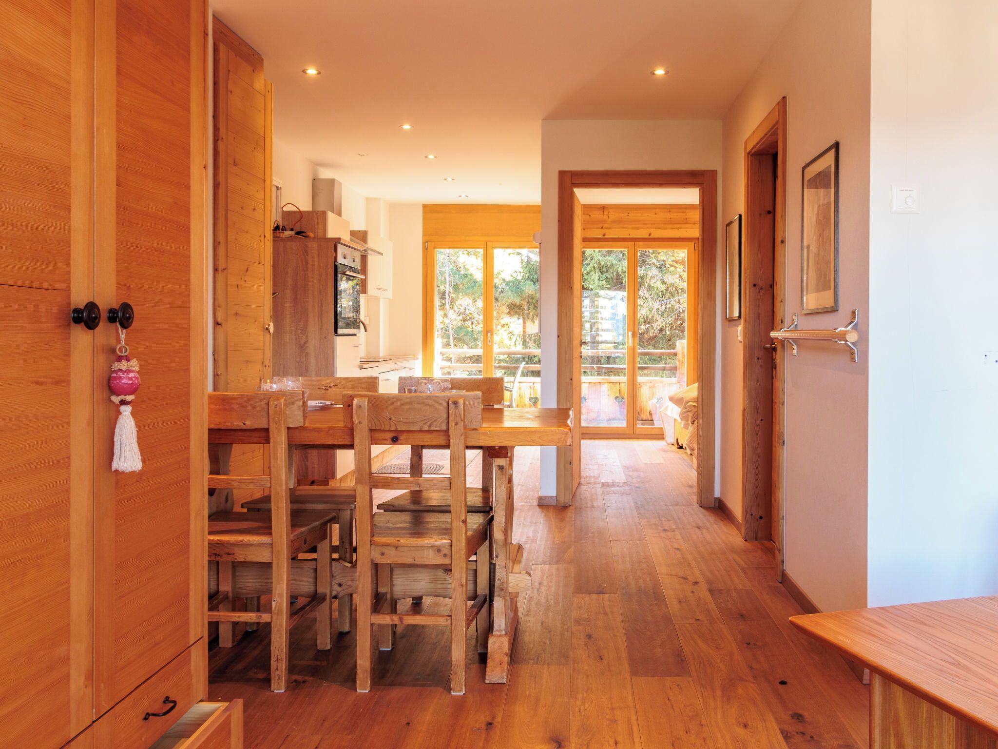 Un intérieur en bois comprenant un coin repas, une cuisine et une porte-fenêtre coulissante donnant sur une terrasse extérieure.