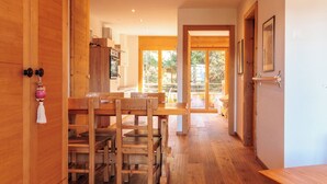 Un intérieur en bois comprenant un coin repas, une cuisine et une porte-fenêtre coulissante donnant sur une terrasse extérieure.
