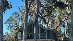 A large, two-story house with a covered porch and multiple windows, surrounded by trees and a small body of water. - Lakefront Retreat - 3BR/2BA Cherry Lake Home + Private Boat Dock (Madison)