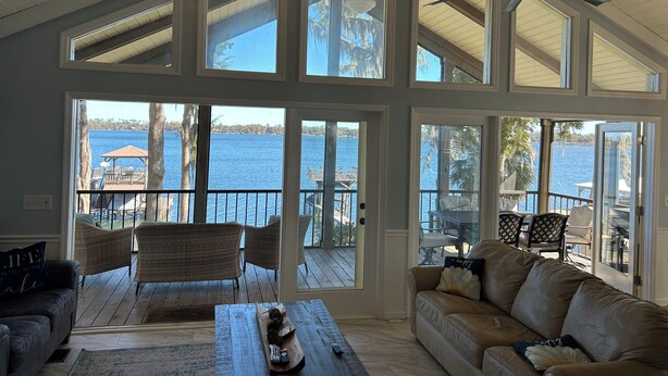 A spacious living room with large windows, a ceiling fan, and a view of the water. - Lakefront Retreat - 3BR/2BA Cherry Lake Home + Private Boat Dock (Madison)