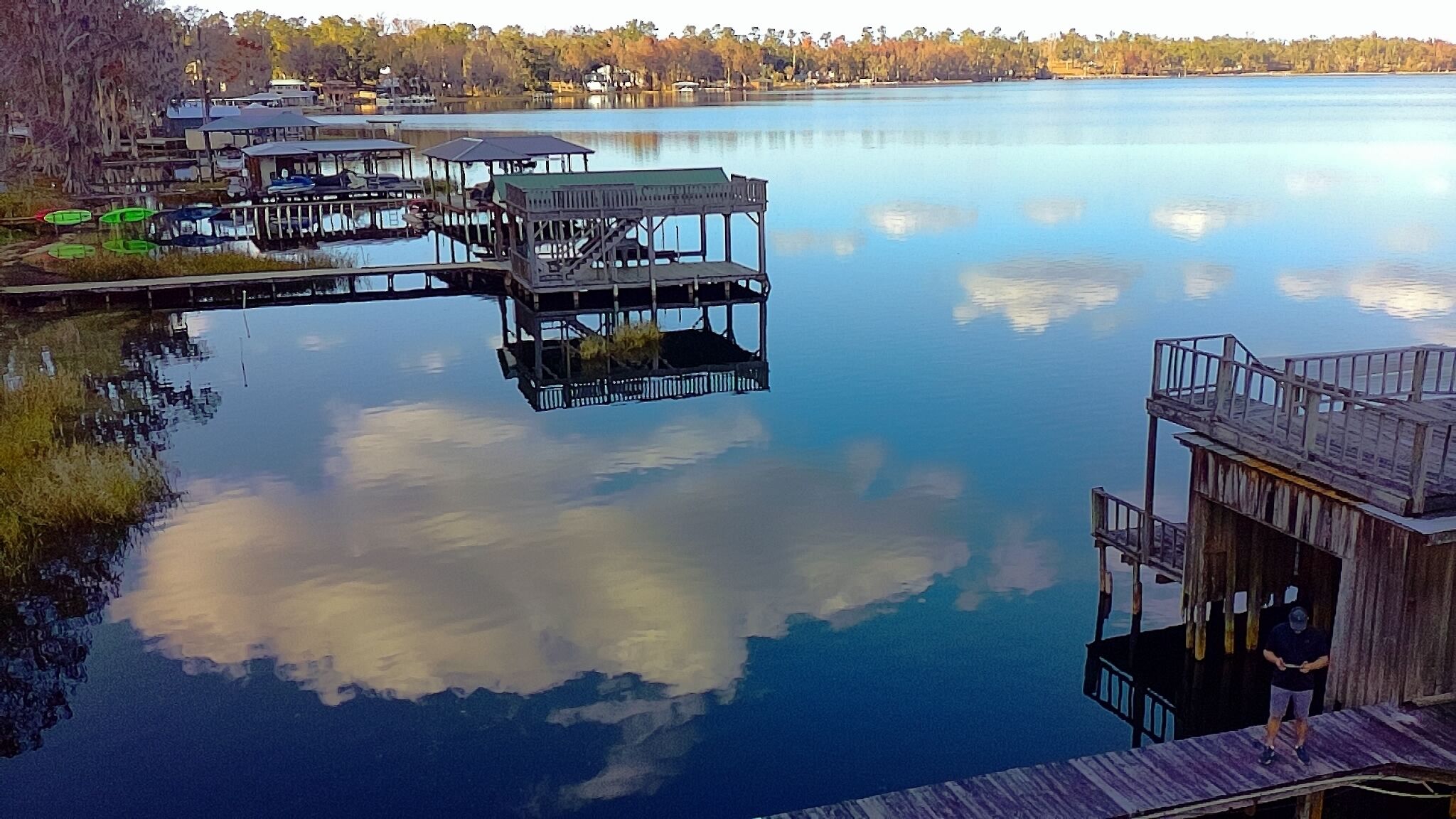 A calm lake with wooden docks and a wooden structure with a balcony.