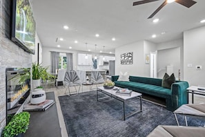 A modern living room with a fireplace, a sofa, and a dining area.