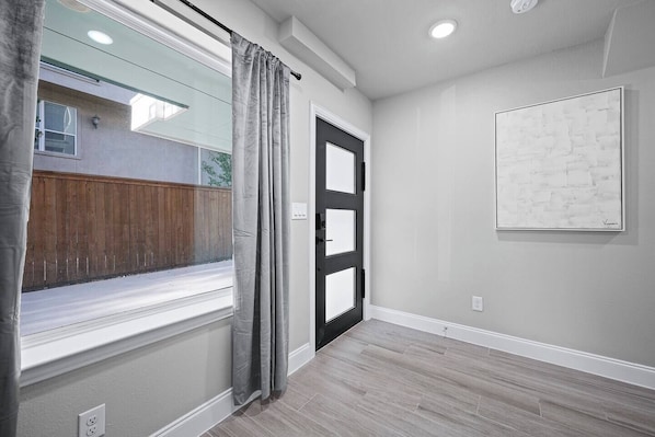 A hallway with a window, a door, and a wall-mounted artwork.
