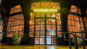 Un edifici amb una entrada gran d'arc i el nom "Chapman & Kirby" il·luminat sobre les portes.