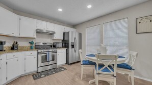 A modern kitchen with white cabinets, stainless steel appliances, and a dining area with blue cushioned chairs. - Cozy Retreat Round Rock|Near Dell|Kalahari|Family (Round Rock)