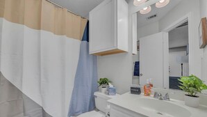 A modern bathroom with a shower curtain, toilet, sink, and mirror. - Cozy Retreat Round Rock|Near Dell|Kalahari|Family (Round Rock)