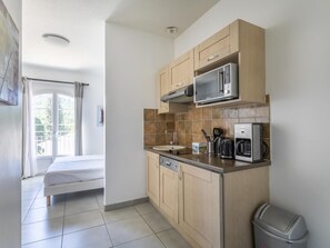 A compact kitchen with wooden cabinets, a microwave, a coffee maker, and a trash bin. - Domaine de Camiole St2b (Callian)