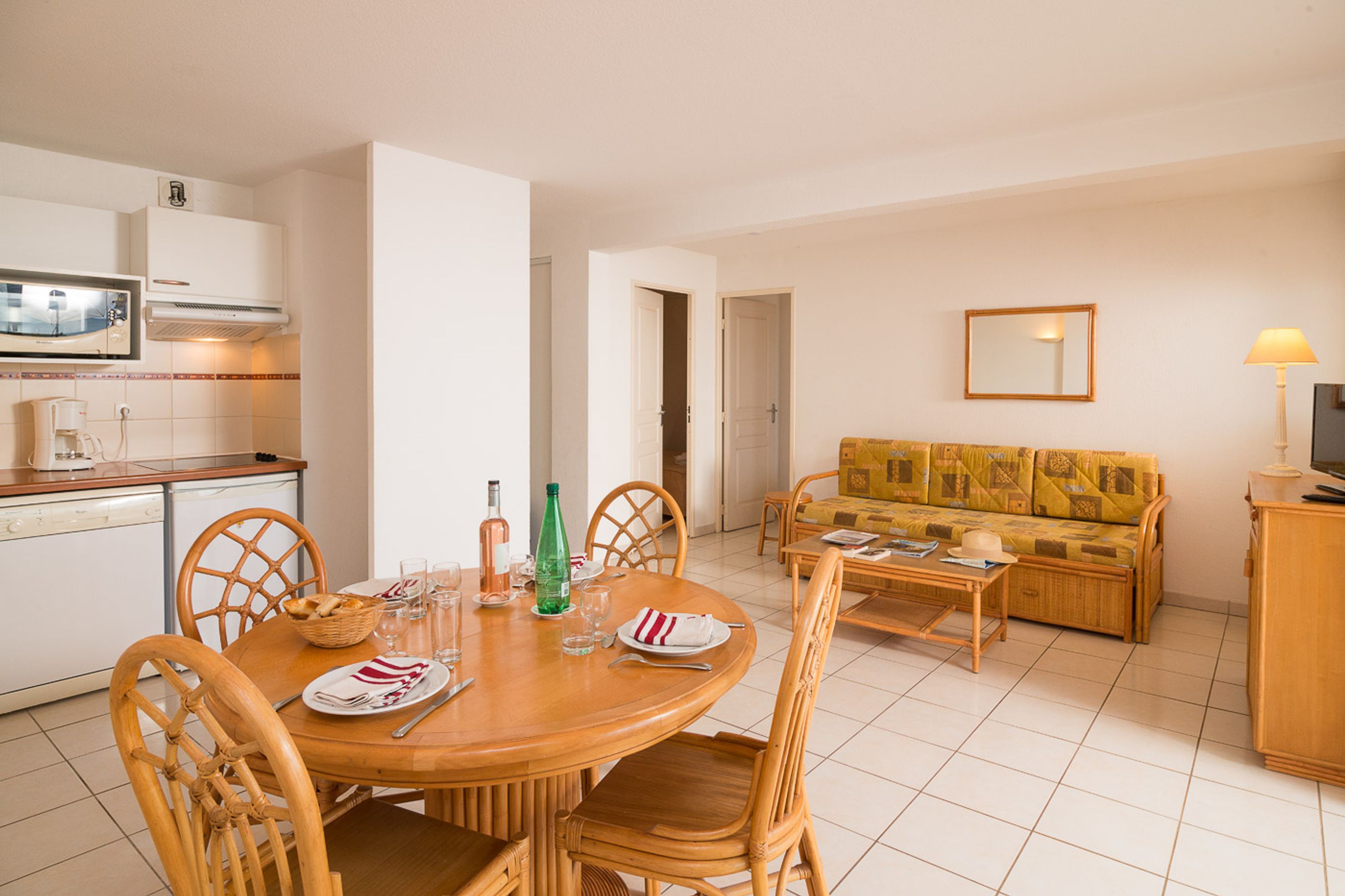 A dining area with a round table, chairs, and a sofa in the background.