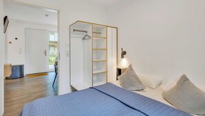 Un dormitorio con una cama, un armario y una mesita de noche.