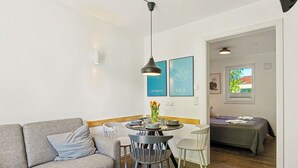 A modern living room with a grey sofa, a round dining table with chairs, a pendant light, and framed cityscape pictures on the wall. - Seewind 601 (Seenähe) by Interhome (Lembruch)