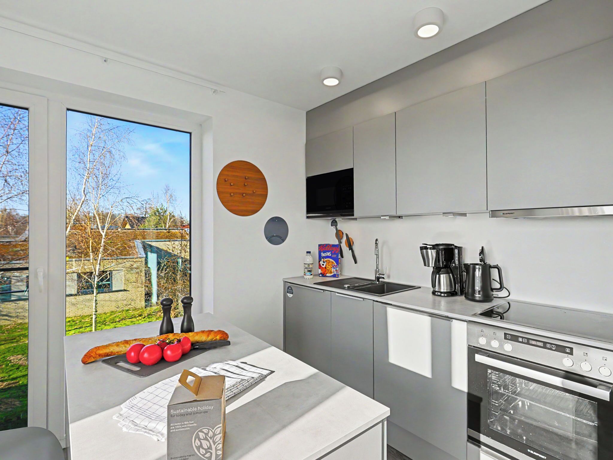 A modern kitchen with a large window, a microwave, a coffee maker, and an oven.