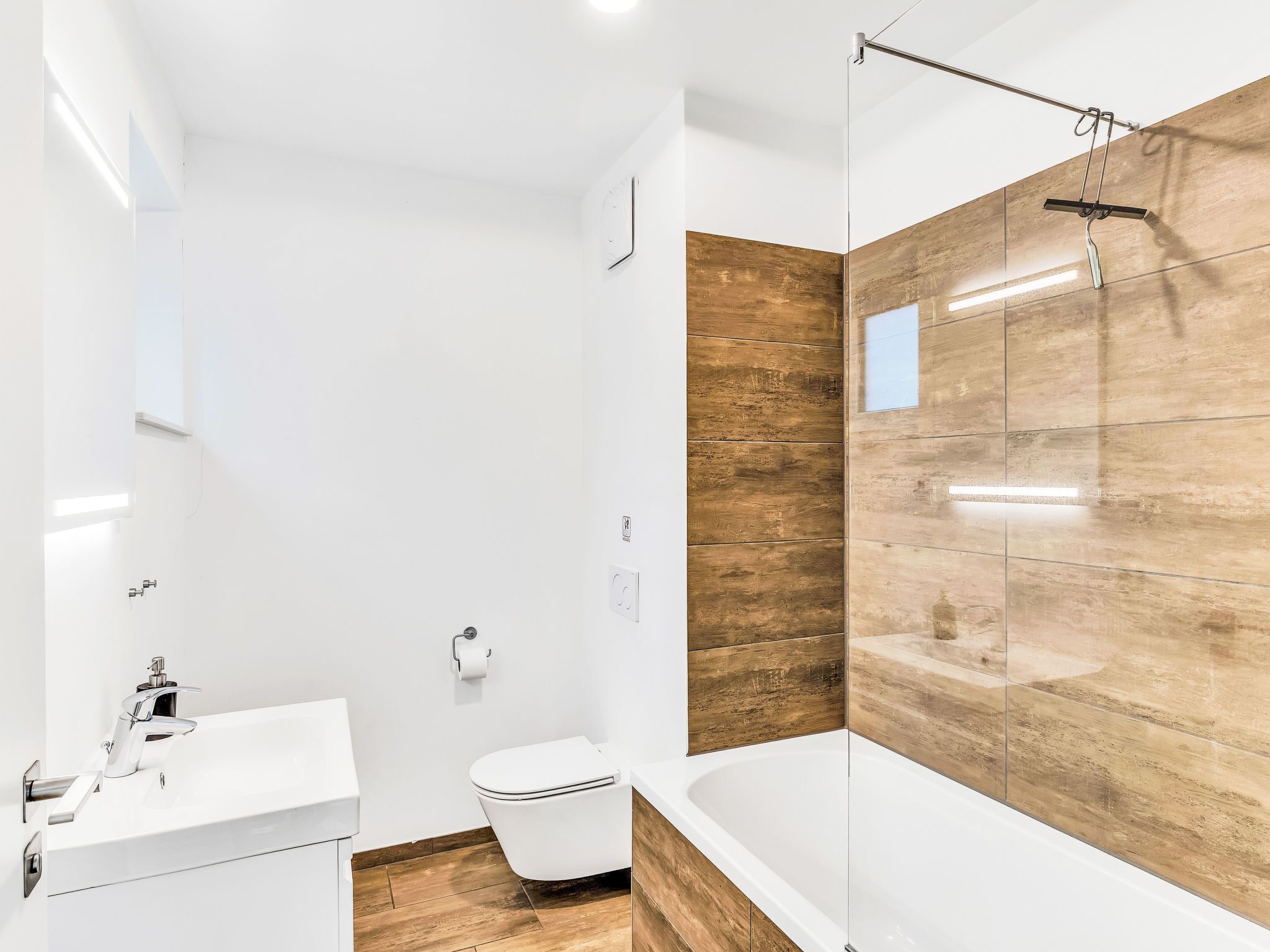Een moderne badkamer met een wit wastafelmeubel, toilet en bad.