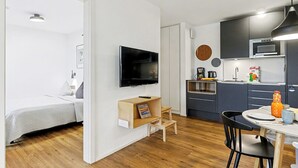 A modern, compact apartment with a kitchenette, a dining area, and a bedroom.